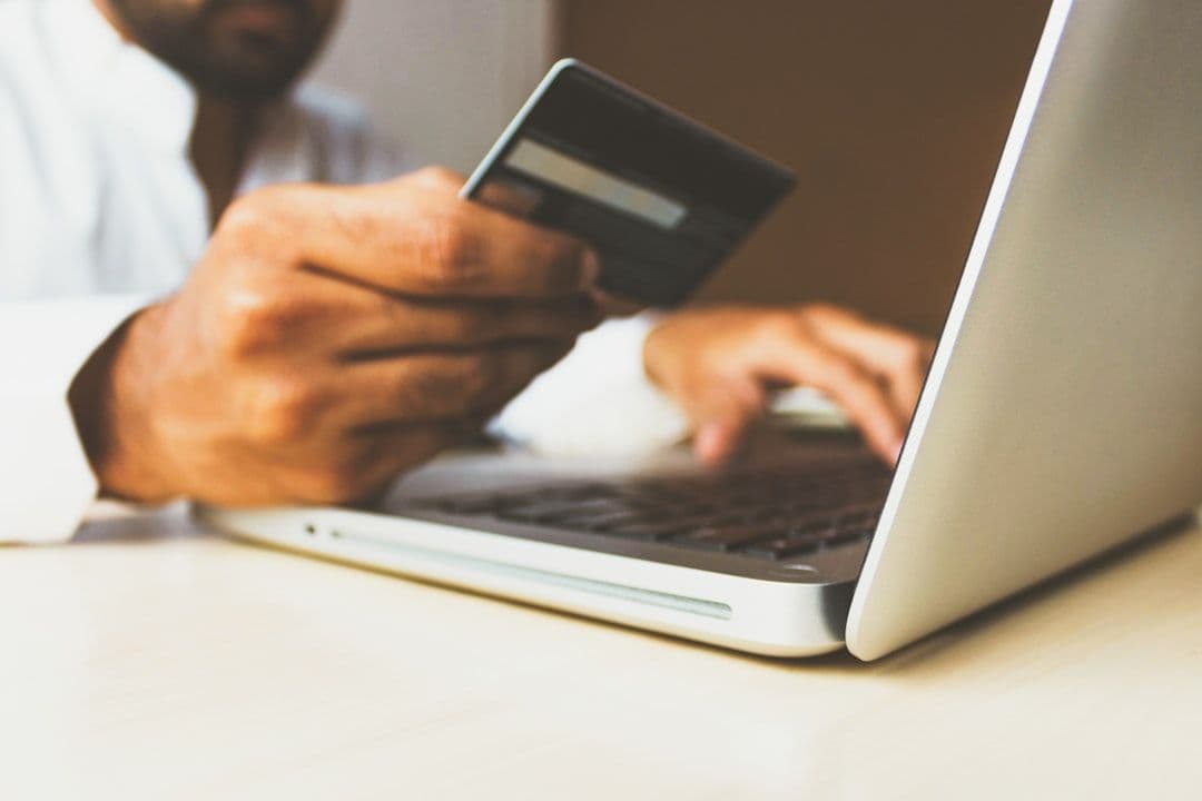 Person using a laptop while holding a credit card